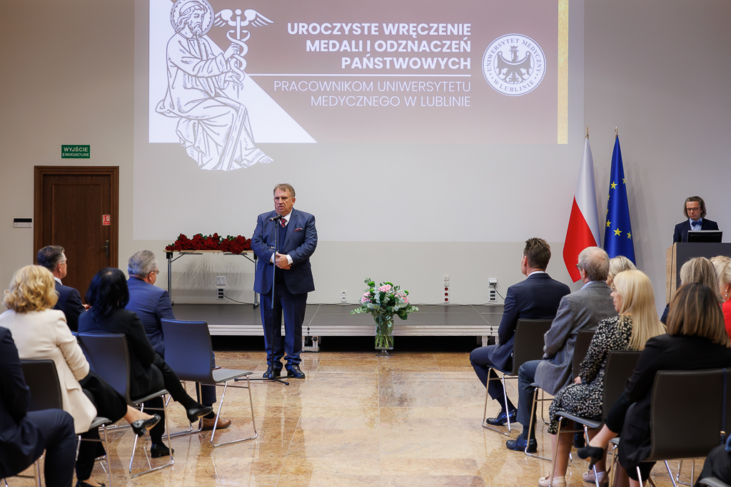 Prof. Wojciech Załuska stoi przed mikrofonem przed publicznością.