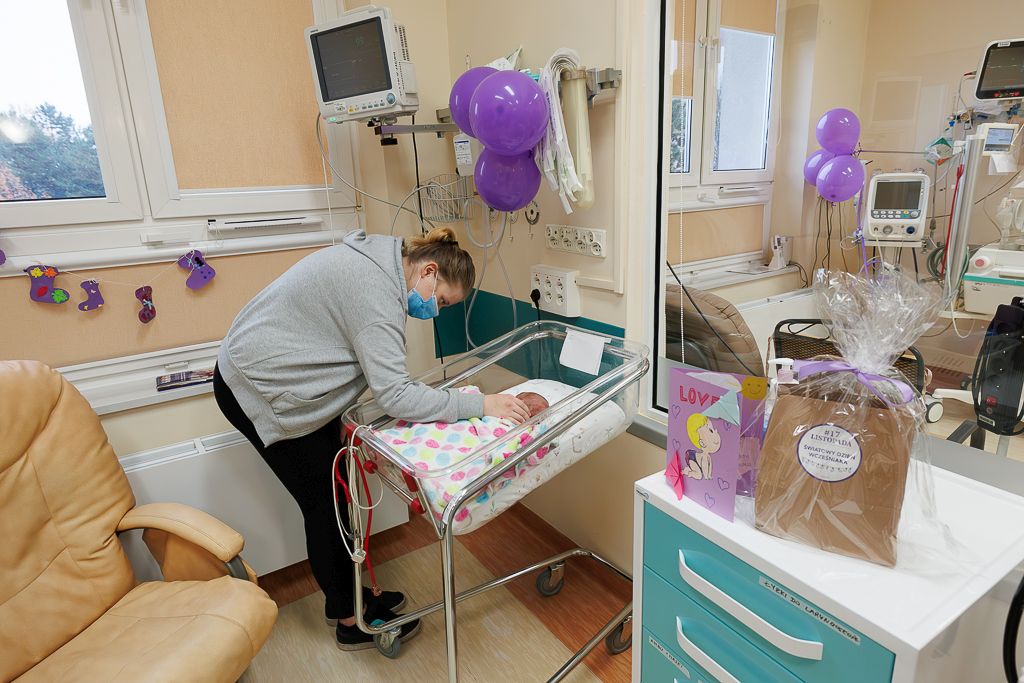 Jedna z mam razem ze swoim dzieckiem. Na szafce prezent z okazji Światowego Dnia Wcześniaka oraz laurka