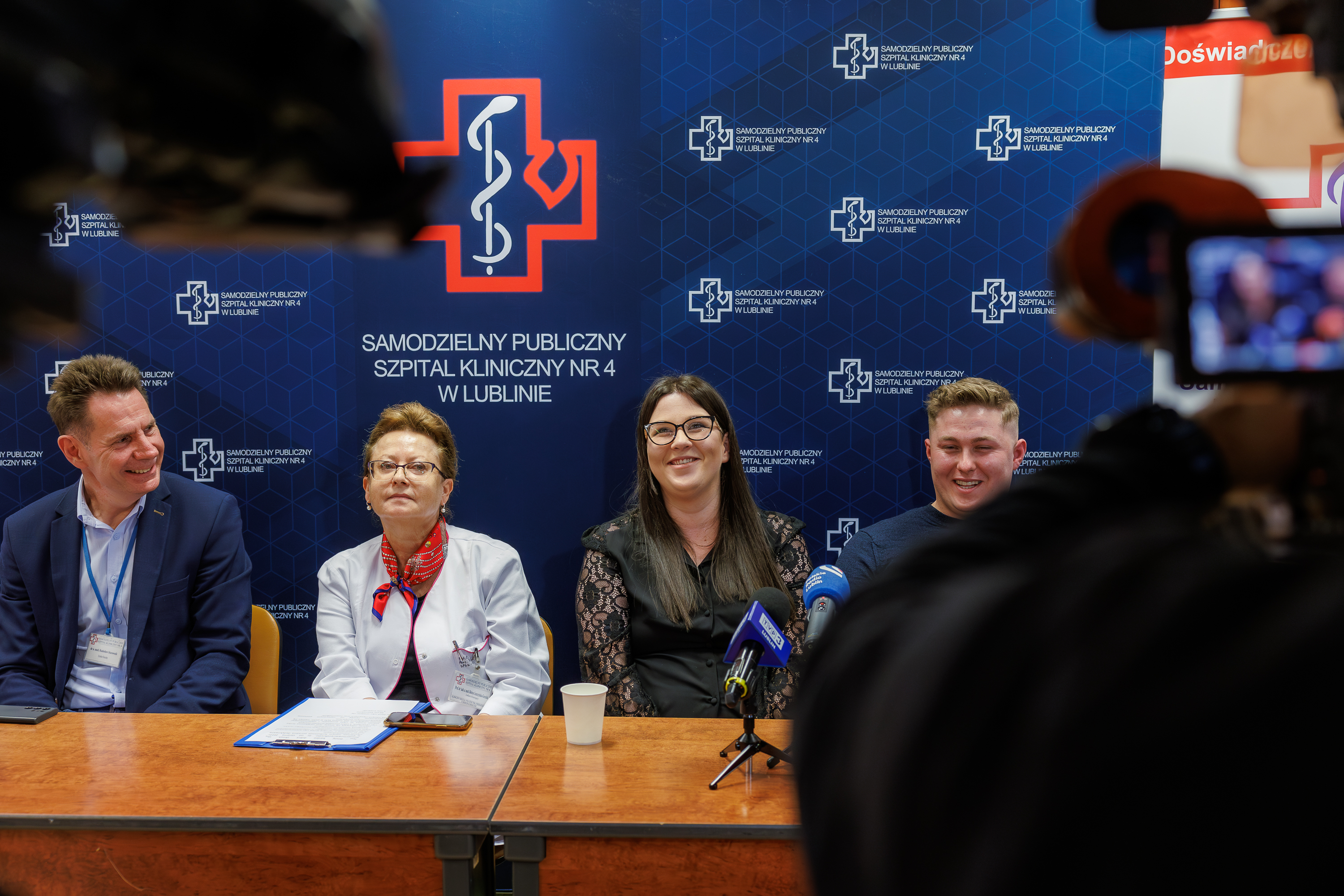 Za stołem siedzą od lewej: dr n. med. Radosław Starownik, dyrektor naczelny Samodzielnego Publicznego Szpitala Klinicznego Nr 4 w Lublinie, prof. dr hab n. med. Bożena Leszczyńska-Gorzelak, kierownik Klinicznego Oddziału Położnictwa, Perinatologii i Chorób Kobiecych SPSK Nr 4 w Lublinie, Paulina i Marcin Sarneccy. Z tyłu ścianka z napisami "Samodzielny Publiczny Szpital Kliniczny Nr 4 w Lublinie"