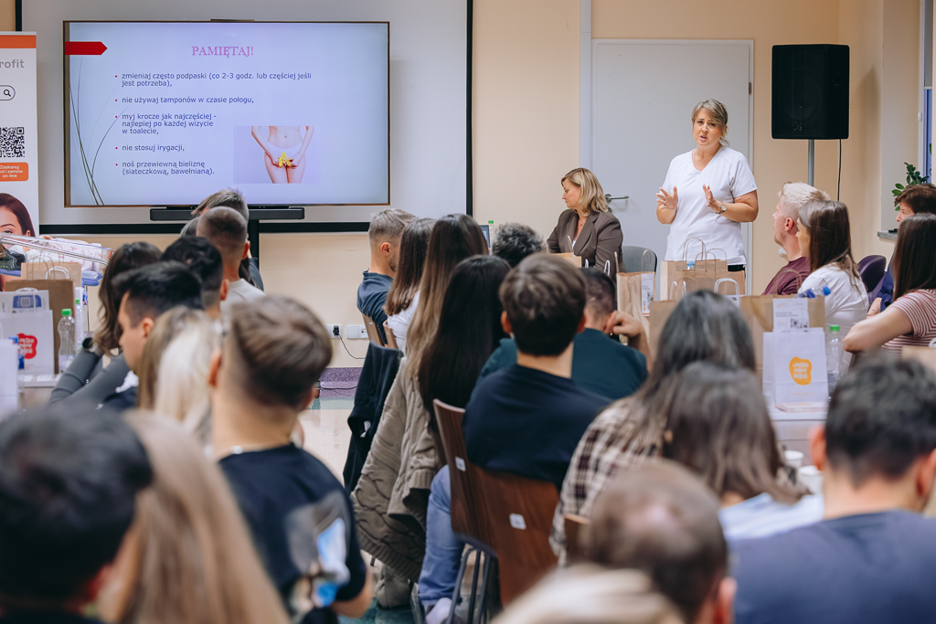 Stojąca z lewej strony Joanna Lisowska opowiada zebranym o tym jak przebiega połóg. Na pierwszym planie uczestnicy szkolenia.