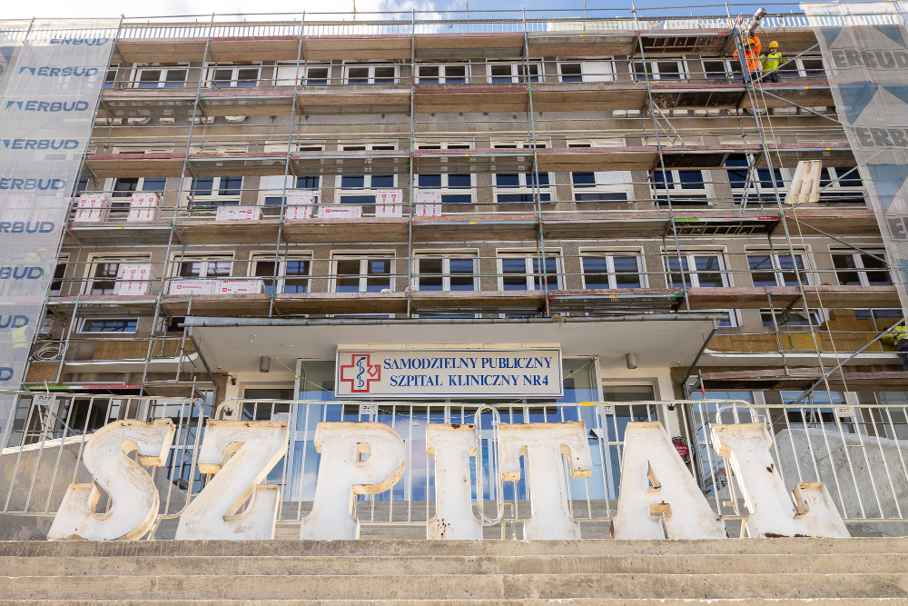 Wejście główne do szpitala. Przed barierkami ustawione zdemontowane litery „szpital”