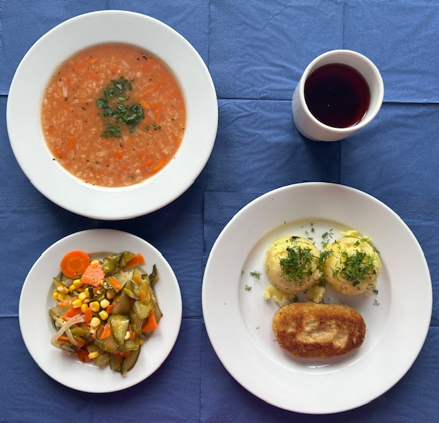na talerzach zupa pomidorowa z ryżem, ziemniaki, kotlet drobiowo- warzywny, surówka z ogórka kiszonego, marchewki i cebuli, w kubku kompot 