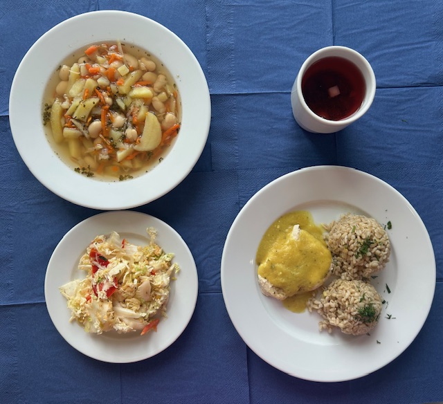 na talerzach zupa fasolowa, bitka drobiowa, sos curry, kasza jęczmienna, surówka z kapusty pekińskiej, papryki z sosem vinegret, w kubku kompot