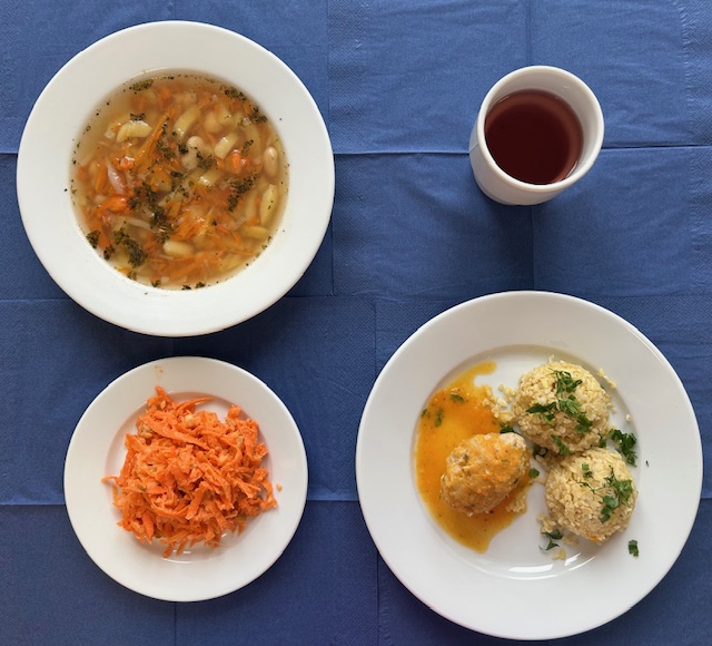 na talerzach zupa fasolowa, pulpet mięsny, sos jarzynowy, kasza bulgur, surówka z marchewki, w kubku kompot 