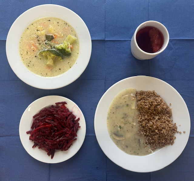 na talerzach zupa brokułowa, kasza gryczana z sosem pieczarkowy, surówka z buraczka jabłka i cebuli, w kubku kompot