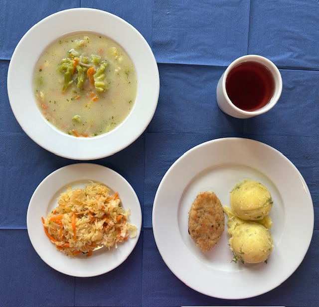 na talerzach zupa brokułowa, kotlet rybny smażony, ziemniaki, surówka z kiszonej kapusty, w kubku kompot