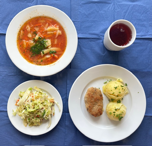 na talerzach zupa pejzanka, kotlet mielony z pieczarką smażony, ziemniaki, surówka z kapusty pekińskiej z papryka i sosem vinegret, w kubku kompot