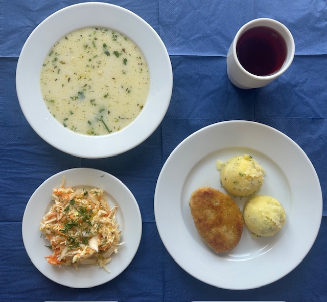na talerzach zupa selerowa z makaronem, ziemniaki, kotlet drobiowo - warzywny, surówka z kapusty pekińskiej z marchewki i sosem vinegret, w kubku kompot 