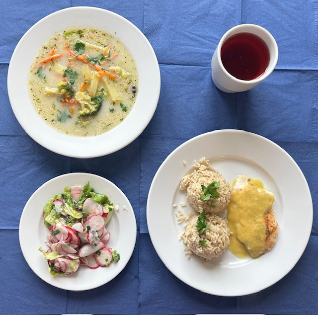 na talerzach zupa brokułowa, bitka drobiowa, sos curry, ryż brązowy, surówka z rzodkiewki, sałaty i szczypioru, w kubku kompot 
