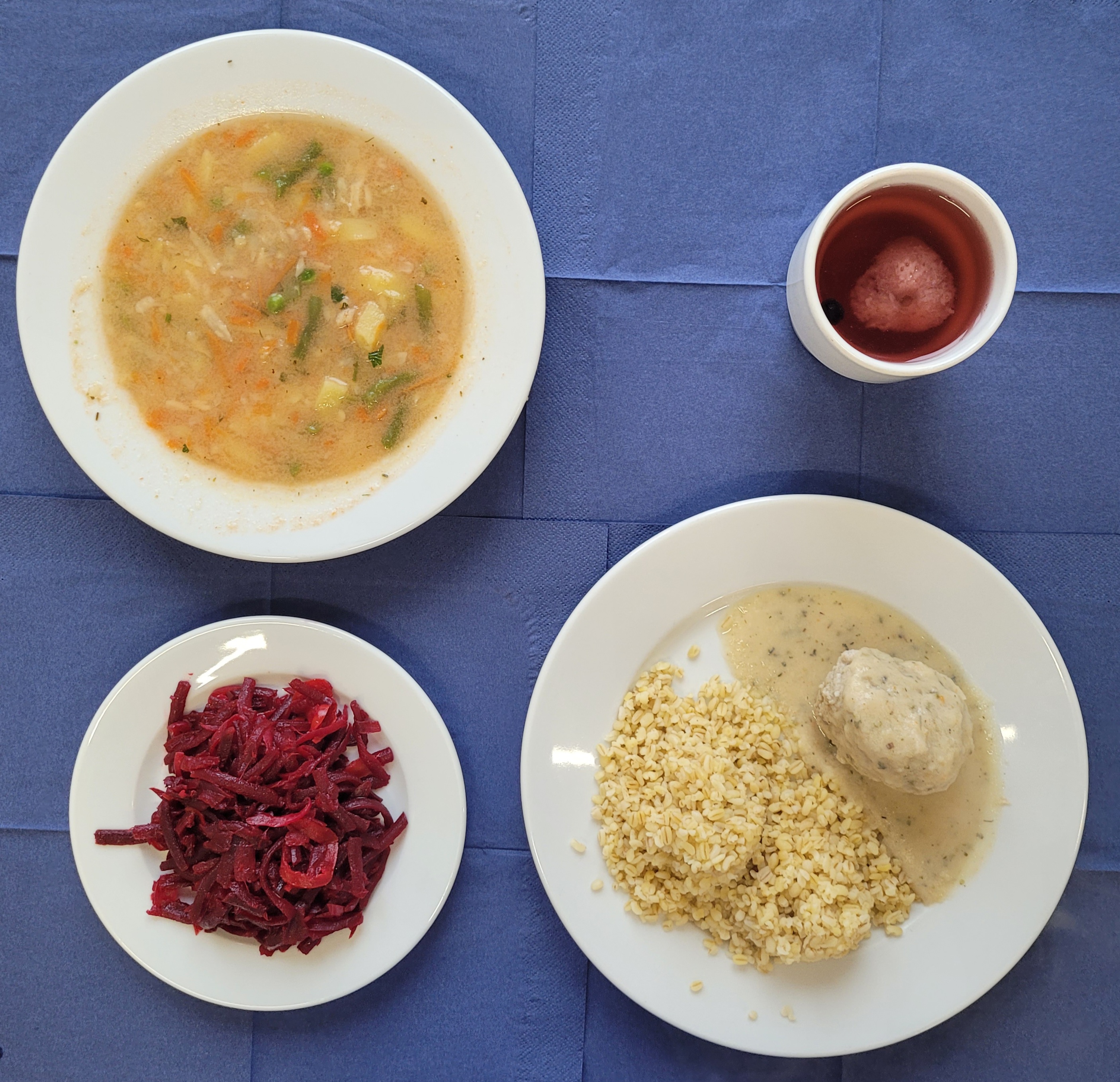 na talerzach pulpet mięsny, sos pietruszkowy, kasza bulgur, surówka z buraczka, jabłka i cebuli, w kubku kompot 