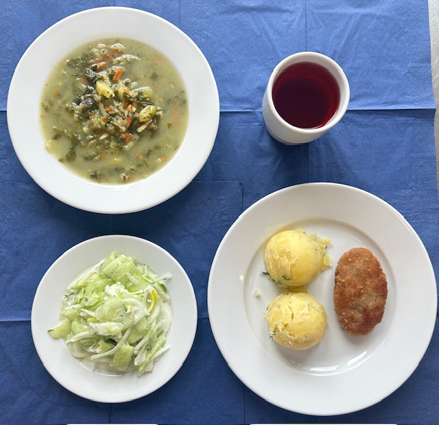na talerzach zupa szpinakowa z ziemniakami, koltet mielony, ziemniaki, mizeria, w kubku kompot 