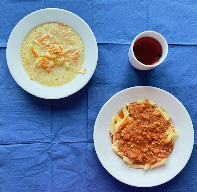 na talerzach zupa jarzynowa, makaron z sosem bolońskim, w kubku kompot 