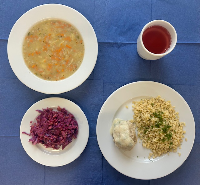 na talerzach zupa krupnik jęczmienny, kasza bulgur, pulpet mięsny, sos pietruszkowy, surówka z czerwonej kapusty, w kubku kompot 