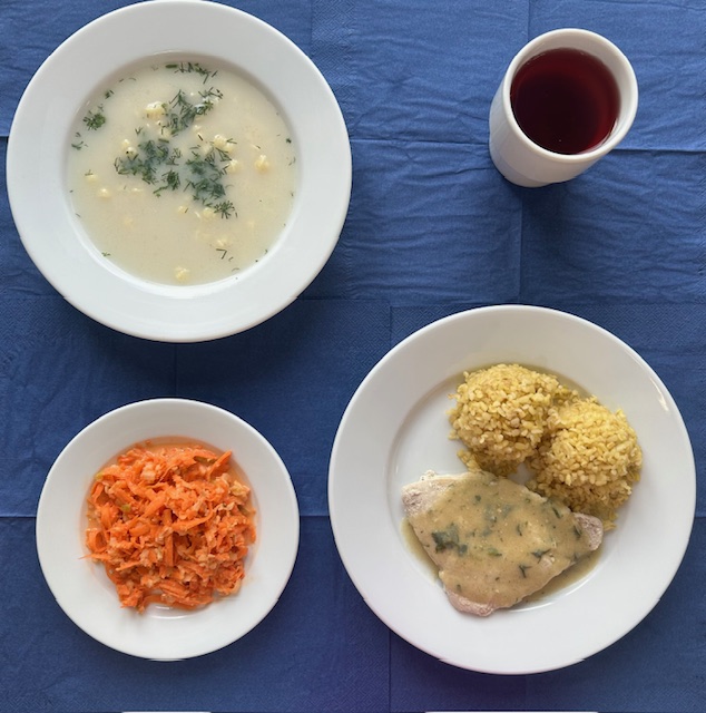 na talerzach zupa selerowa z makaronem, bitka schabowa, sos pietruszkowy, kasza bulgur, surówka z marchewki i jabłka z jogurtem, w kubku kompot 