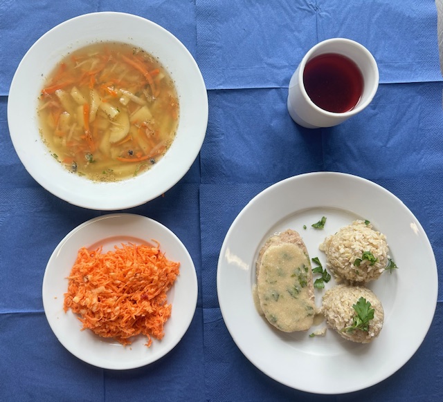 na talerzach zupa grochowa, pieczeń rzymska, sos pietruszkowy, ryz brązowy, surówka z marchewki, jabłka i jogurtu, w kubku kompot 