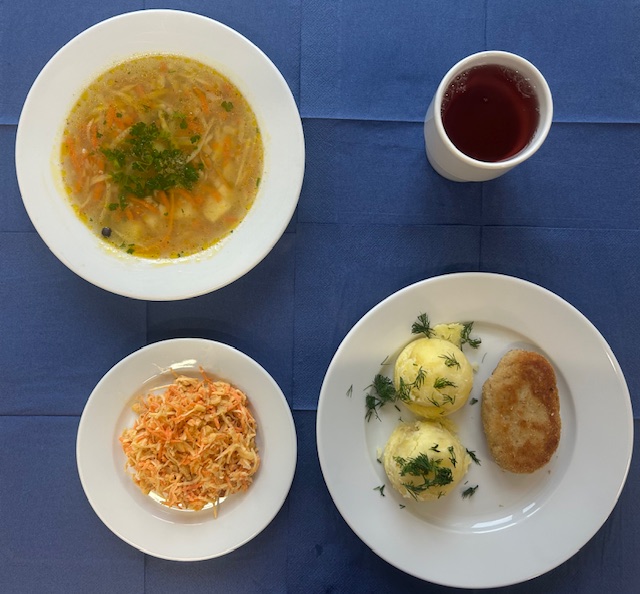 na talerzach zupa krupnik jęczmienny, kotlet rybny, ziemniaki, surówka z jarzyn mieszanych, w kubku kompot 