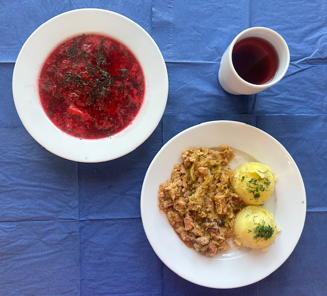 na talerzach zupa botwinkowa, bigos, zimeniaki, w kubku kompot 
