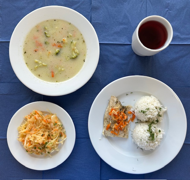 na talerzach zupa brokułowa, ryba morszczuk pieczona, ryz basmati, surówka z kiszonej kapusty w kubku kompot