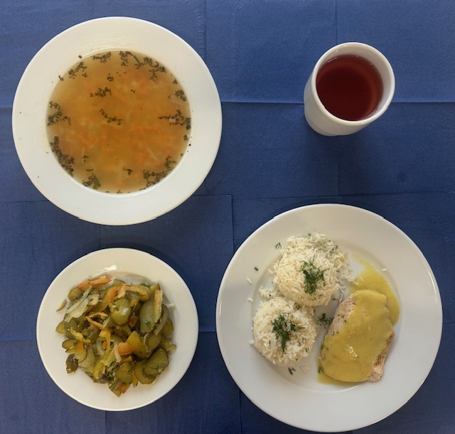 na talerzach zupa fasolowa, ryż paraboliczny, bitka drobiowa, sos curry, surówka z ogórka kiszonego, w kubku kompot 