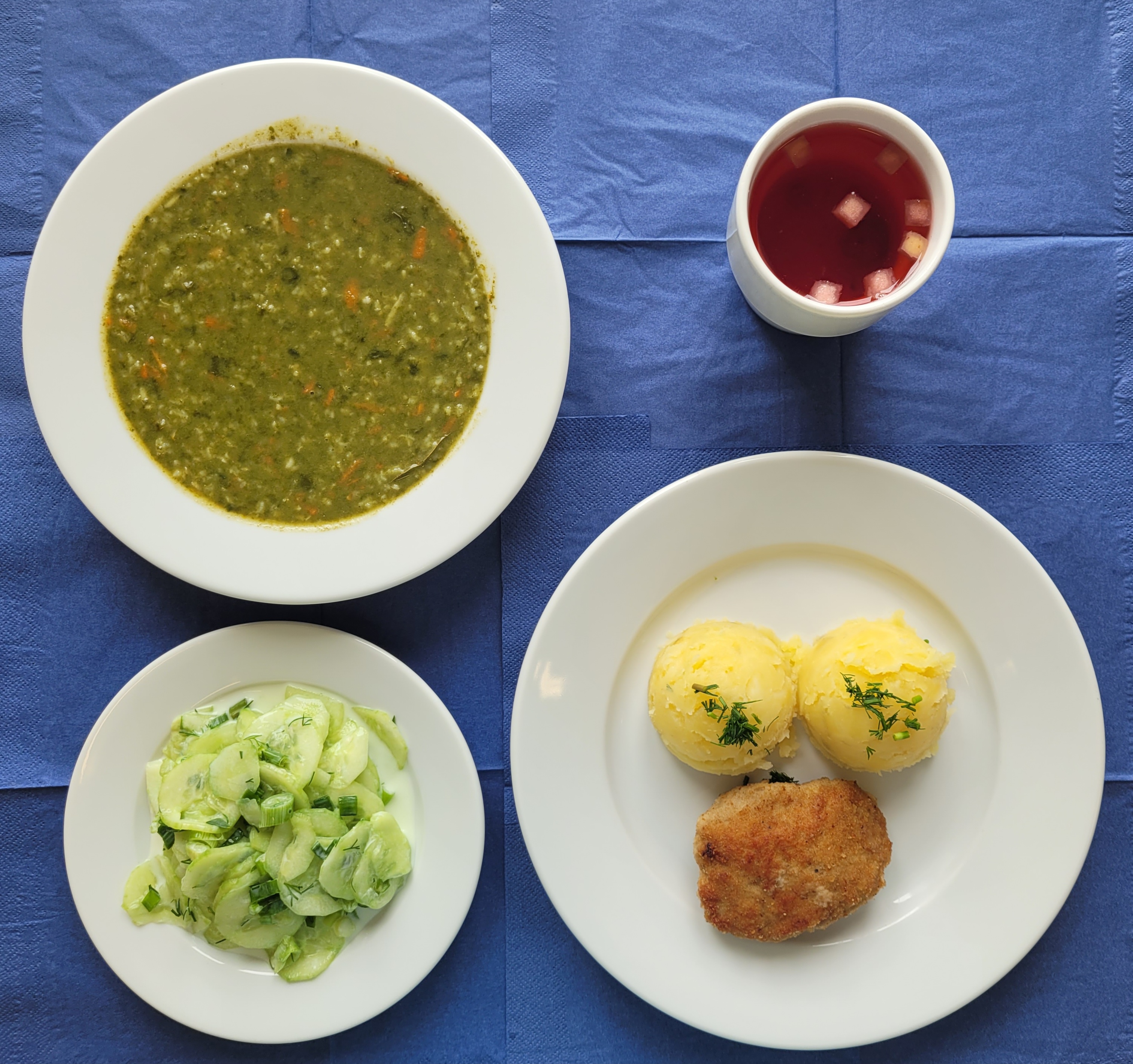 na talerzach zupa szpinakowa z ryżem, kotlet mielony z ziemniakami, mizeria, w kubku kompot 