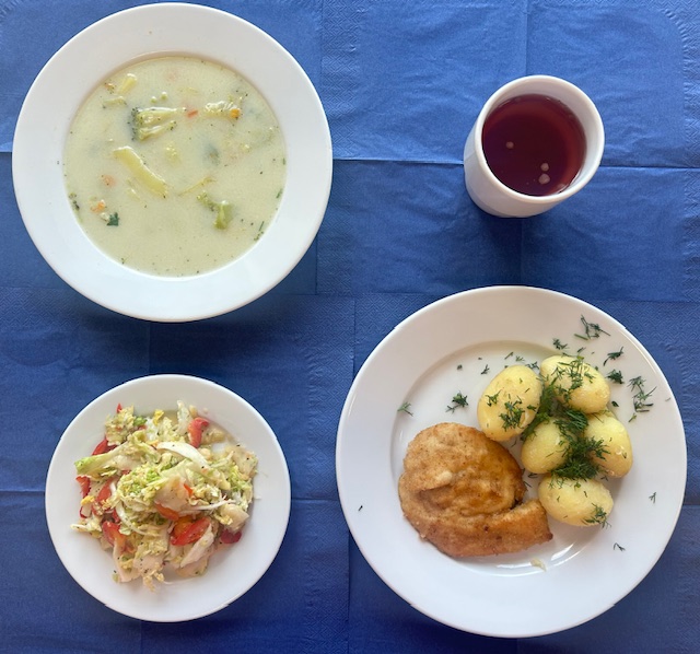 na talerzach zupa brokułowa, kotlet drobiowy panierowany, ziemniaki młode, surówka z kapusty pekińskiej, papryki z sosem vinegret, w kubku kompot
