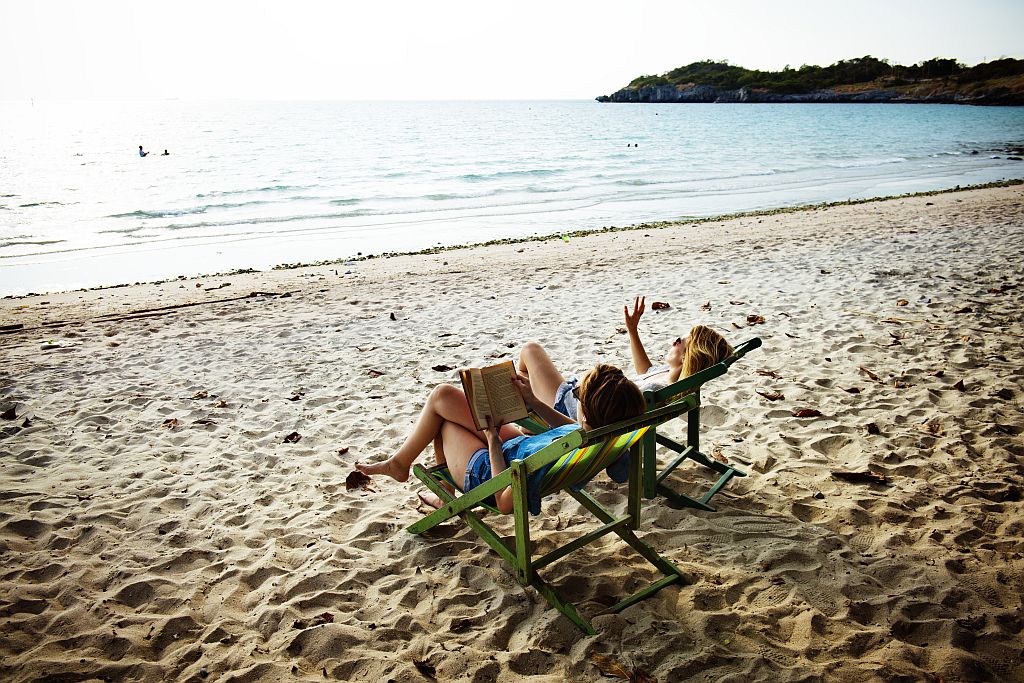 Wakacje. Zdjęcie ilustracyjne, ukazujące dwie kobiety siedzące w leżankach na plaży. Fot. freepik.com