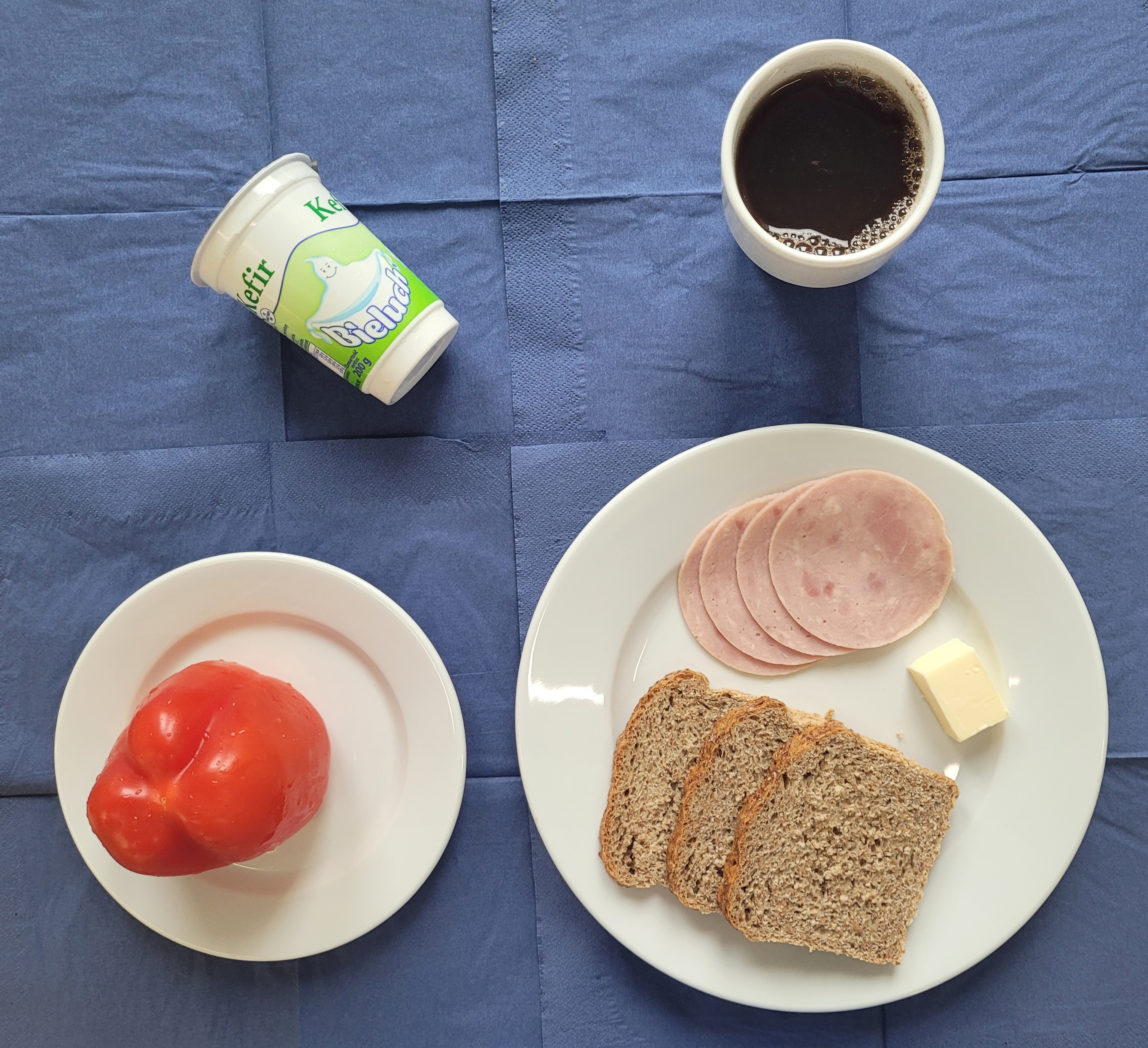 na talerzach chleb razowy, masło, polędwicowa, papryka, kefir, w kubku herbata z cytryną gorzka