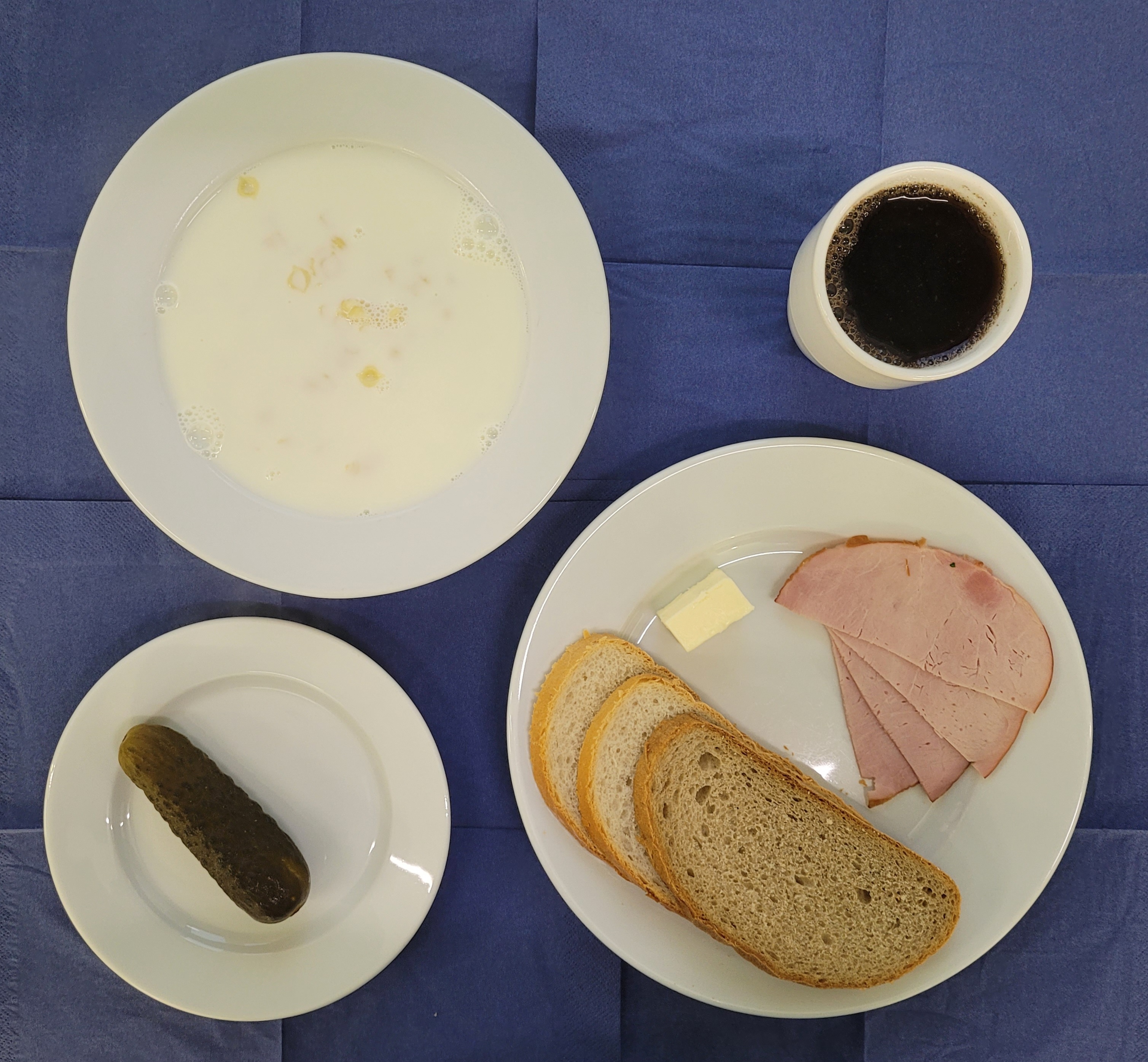na talerzach makaron na mleku, chleb pszenny, chleb sitkowy, masło, szynka gotowana, ogórek kiszony, w kubku herbata z cytryną