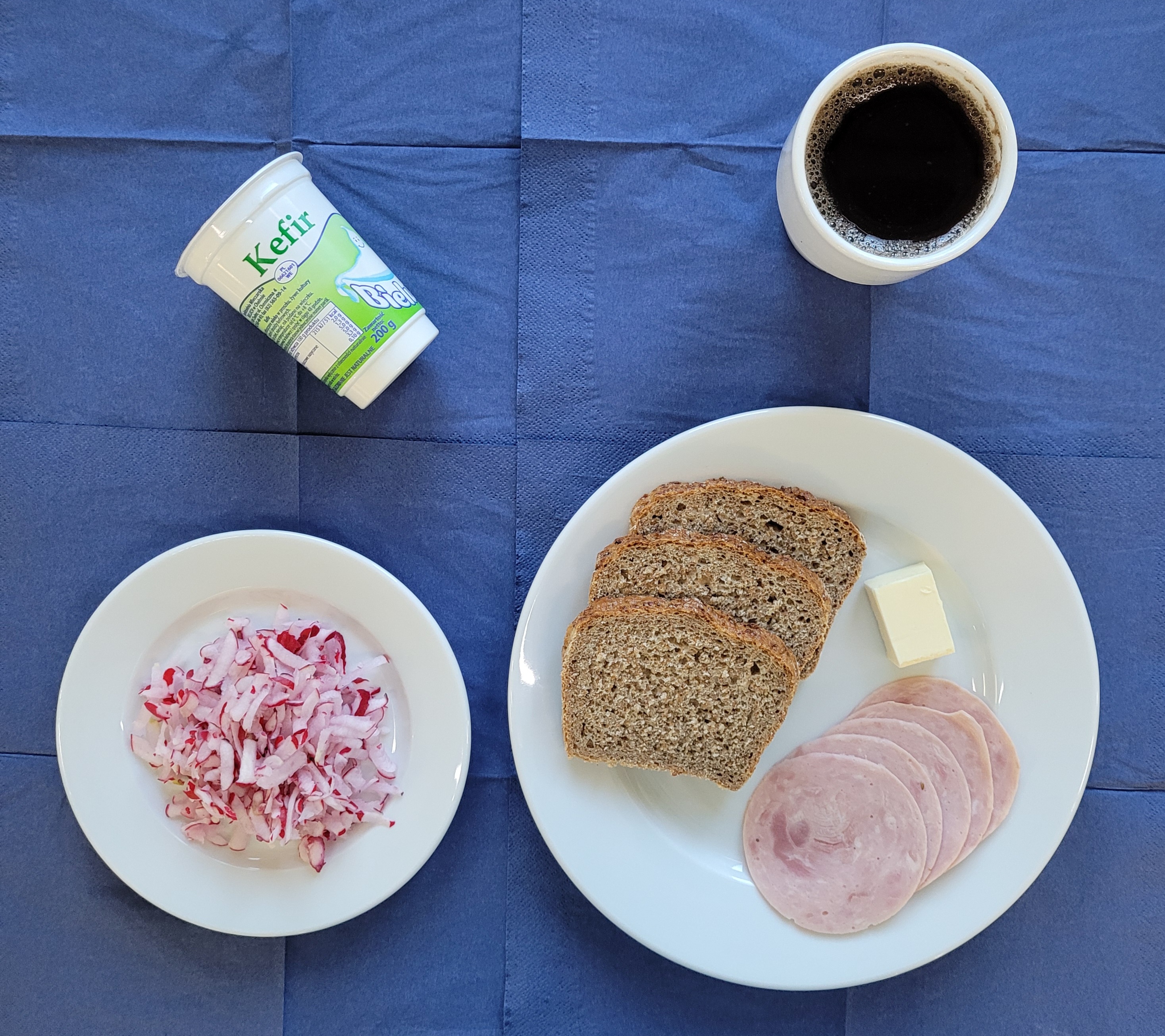 Na talerzach : Polędwicowa, rzodkiewka, chleb razowy, masło, kefir, w kubku herbata z cytryną bez cukru