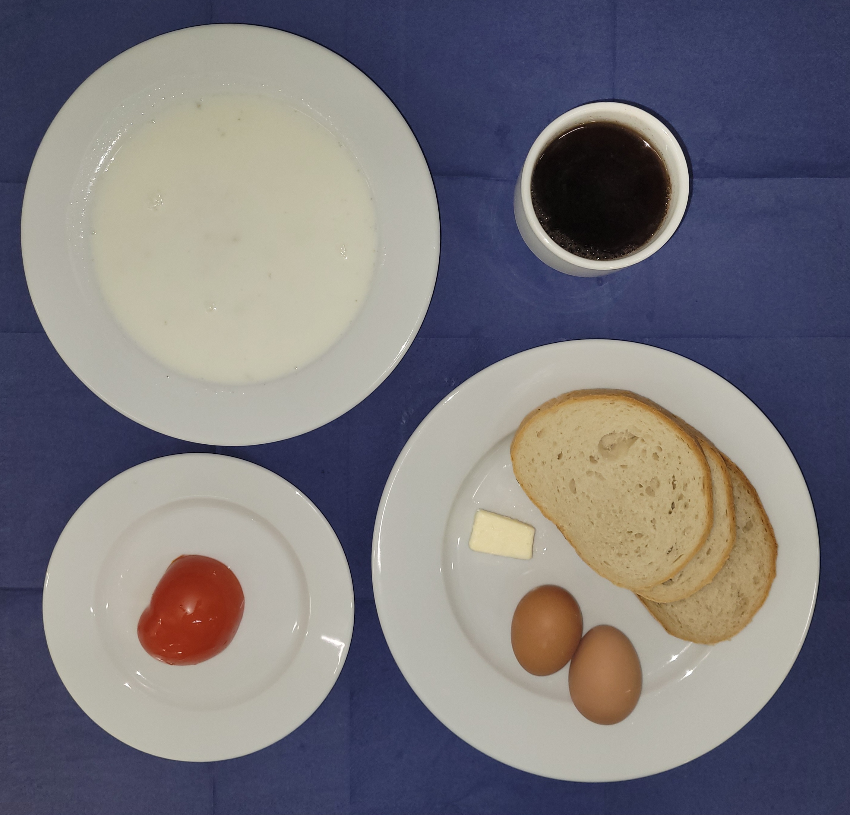 na talerzach płatki owsiane na mleku, chleb pszenny, chleb sitkowy, masło, jajko gotowane 2 sztuki, pomidor, w kubku herbata z cytryną 