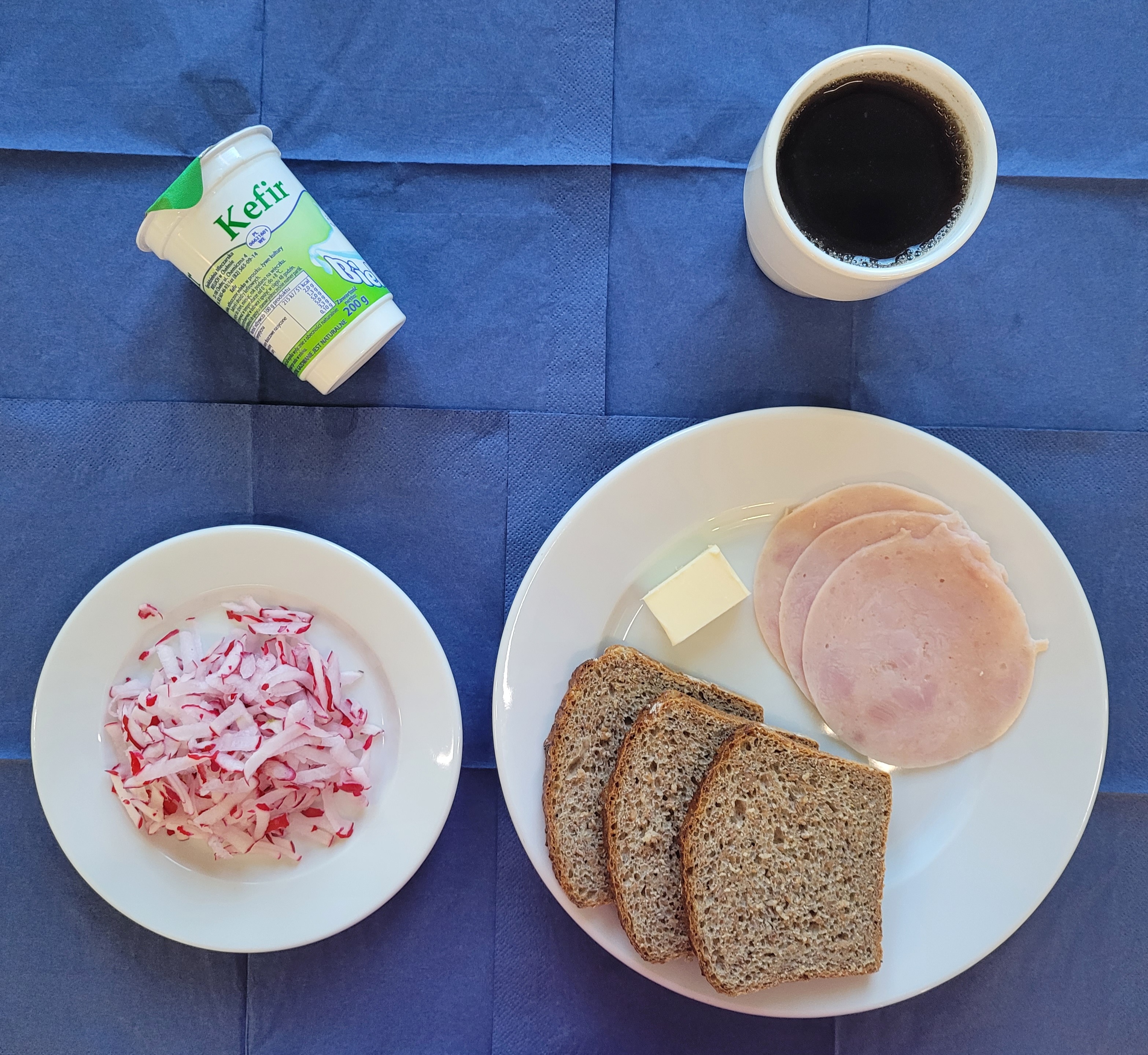 na talerzach chleb razowy, masło, wędlina szynkowa, rzodkiewka, kefir, w kubku herbata z cytryną bez cukru 