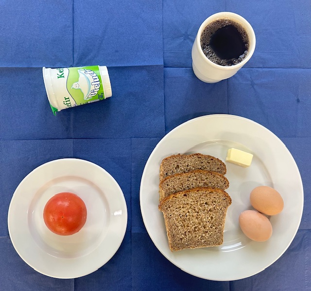 na talerzach chleb razowy, jajko gotowane 2 sztuki, masło, pomidor, kefir, w kubku herbata z cytryną bez cukru