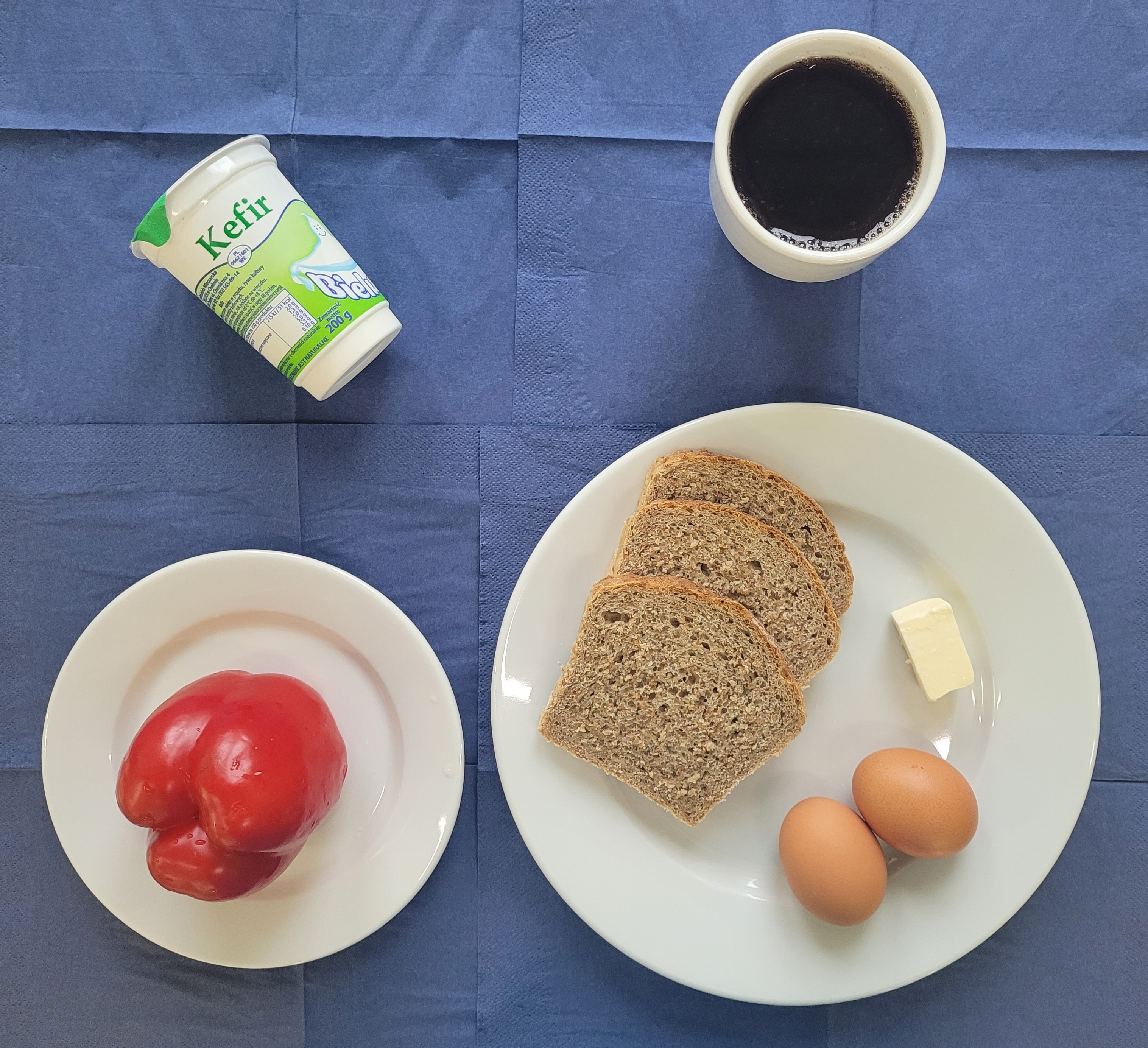 na talerzach chleb razowy, masło, jajko gotowane 2 sztuki, papryka, kefir, w kubku herbata z cytryną gorzka 