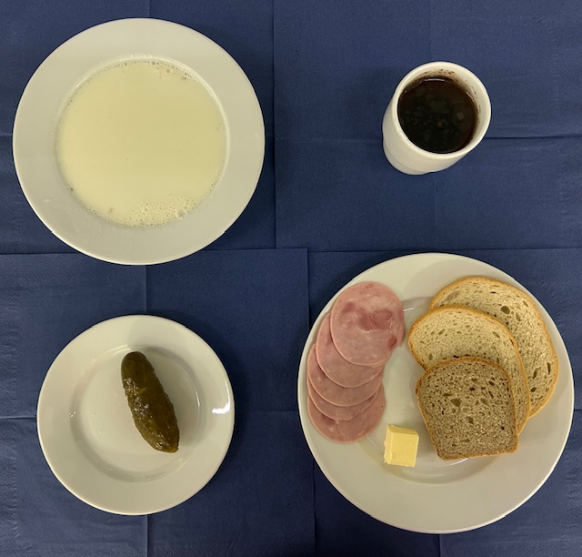 na talerzach płatki jęczmienne na mleku, chleb pszenny, chleb razowy, masło, polędwicowa, ogórek kiszony, w kubku herbata z cytryną 