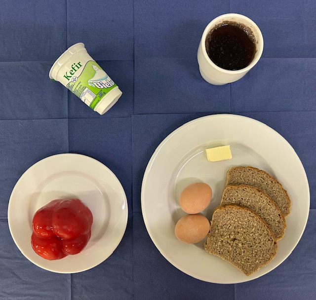 na talerzach chleb razowy, masło, jajko gotowane 2 sztuki, papryka, kefir w kubku herbata z cytryną gorzka 