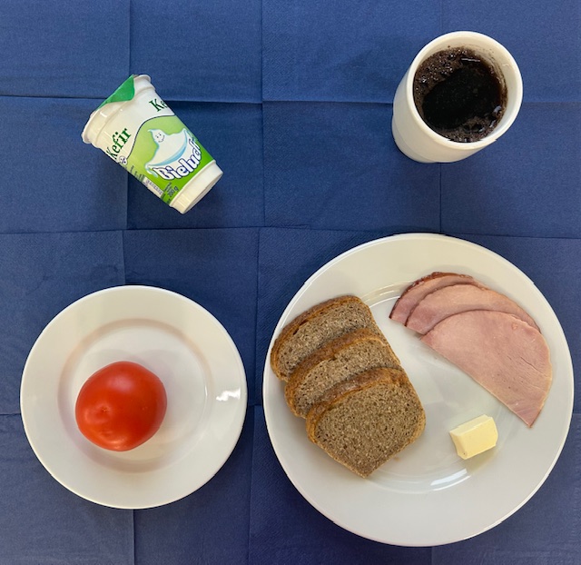 na talerzach chleb razowy, szynka gotowana, masło, pomidor, kefir w kubku herbata z cytryną gorzka 