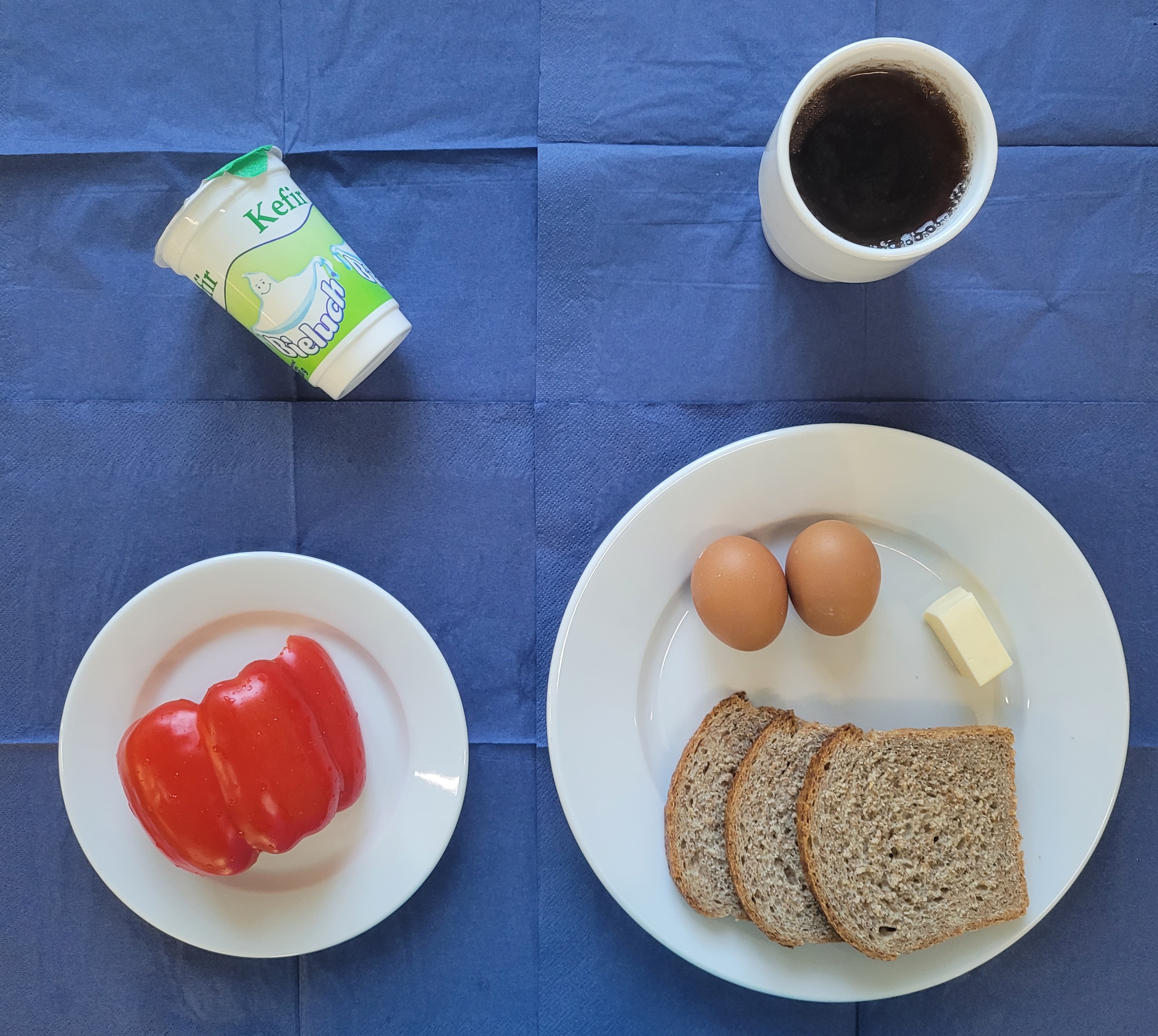 na talerzach chleb razowy, masło, jajko gotowane 2 sztuki, papryka, kefir, w kubku herbata z cytryną 