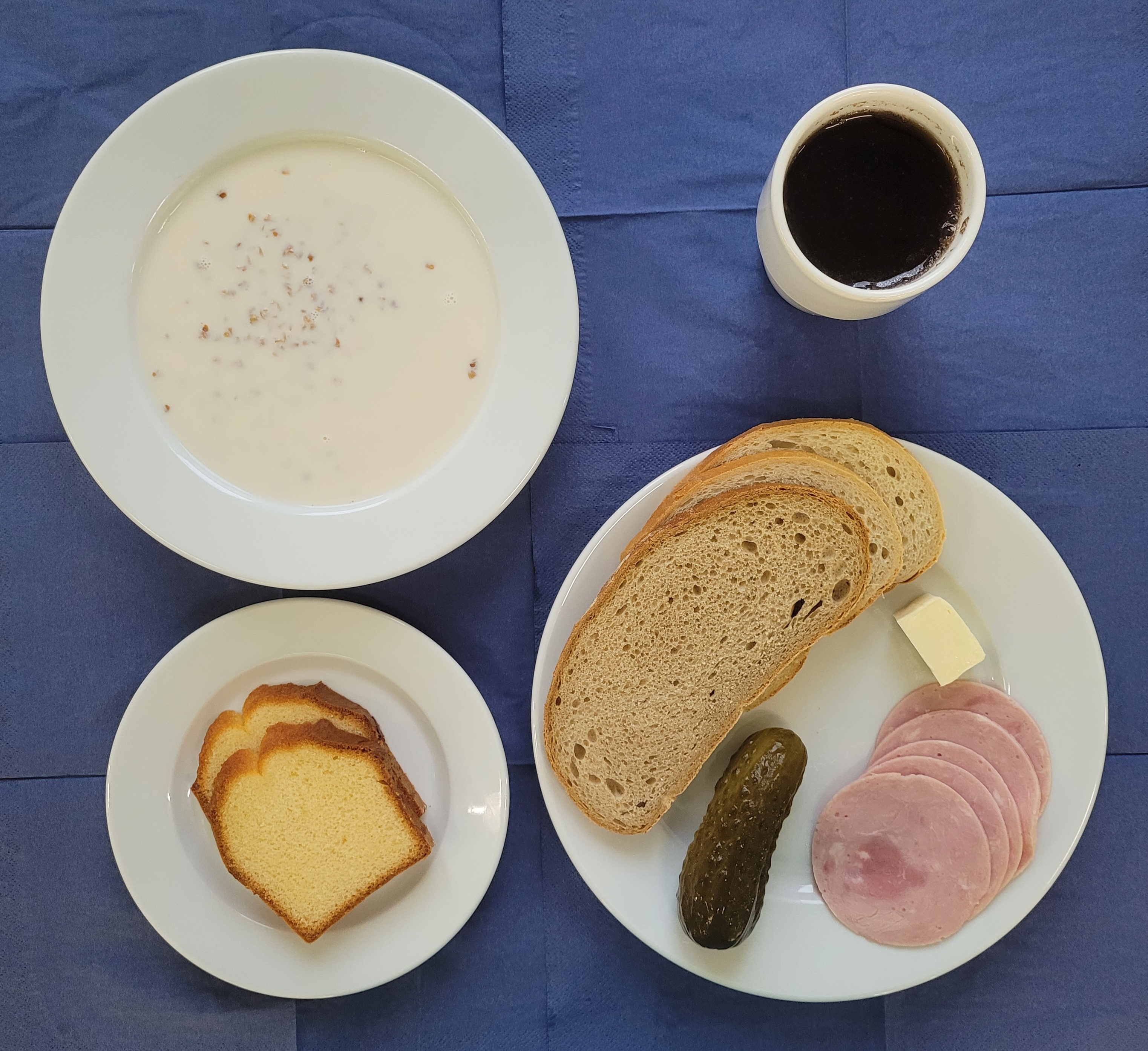 na talerzach kasza gryczana na mleku, chleb zwykły pszenny, chleb sitkowy, masło, polędwicowa, ogórek kiszony, babka jogurtowa, w kubku herbata z cytryną 