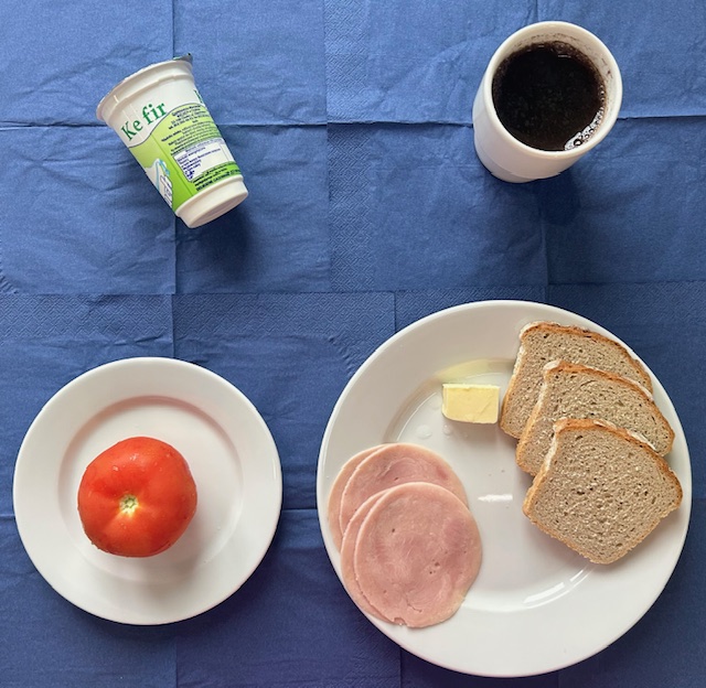 na talerzach chleb żytni, masło, szynkowa, pomidor, kefir w kubku herbata z cytryną