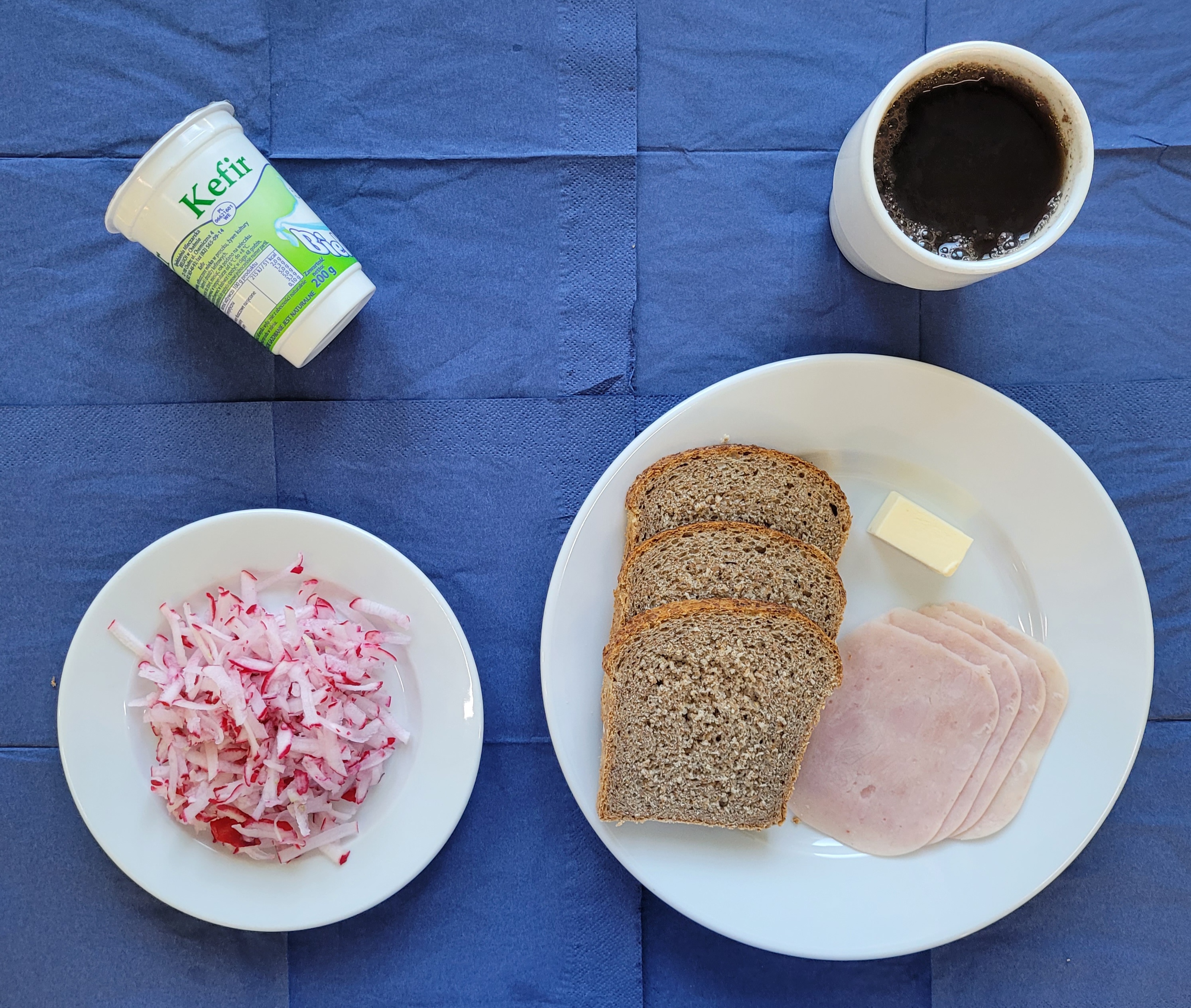 na talerzach szynka lubeslska, chleb razowy, rzodkiewka, masło, kefir, w kubku herbata z cytryną gorzka 