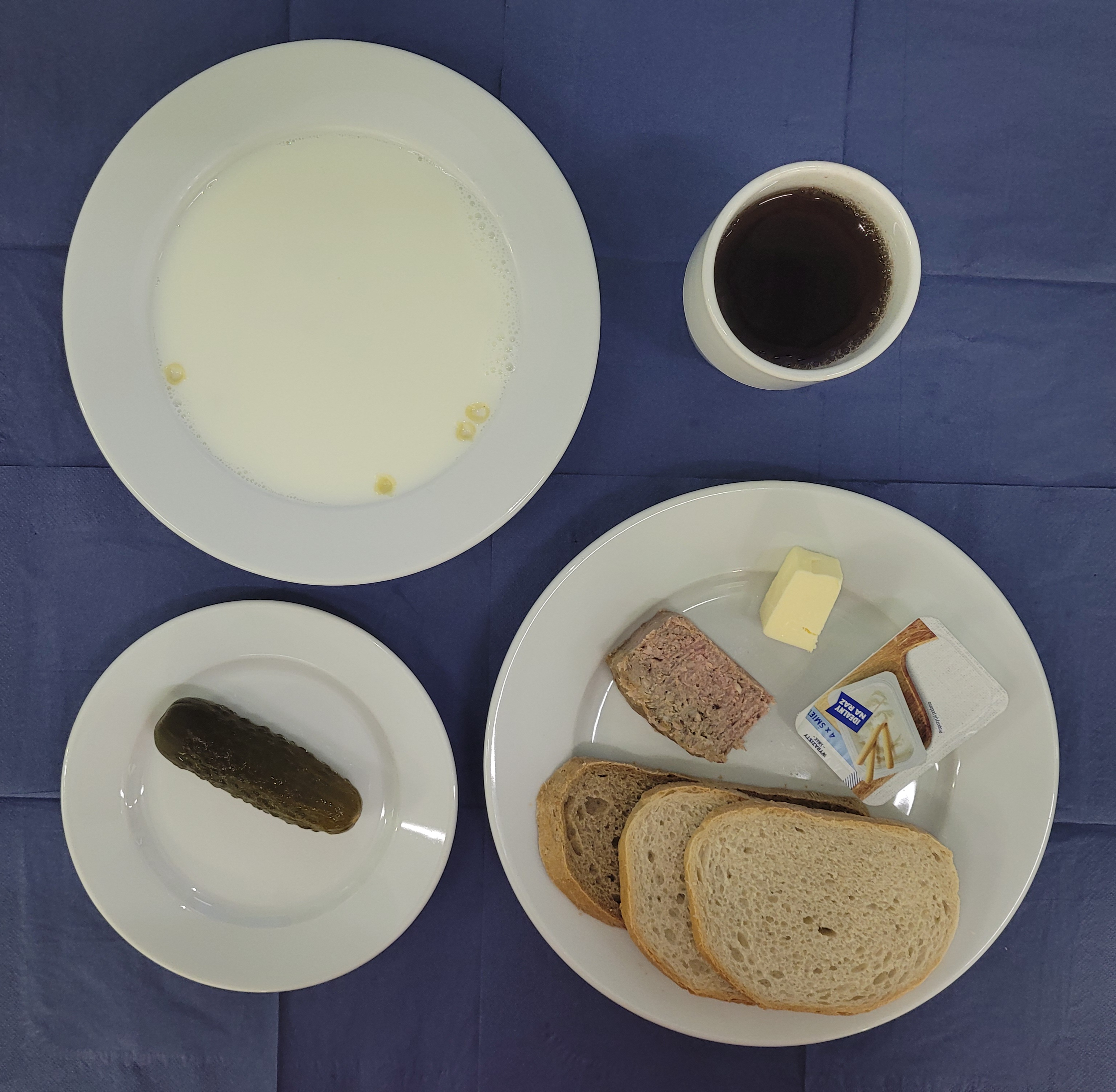 na talerzach makaron na mleku, chleb pszenny, chleb sitkowy, masło, pasztet drobiowy, serek kanapkowy, ogórek kiszony, w kubku herbata z cytryną słodka