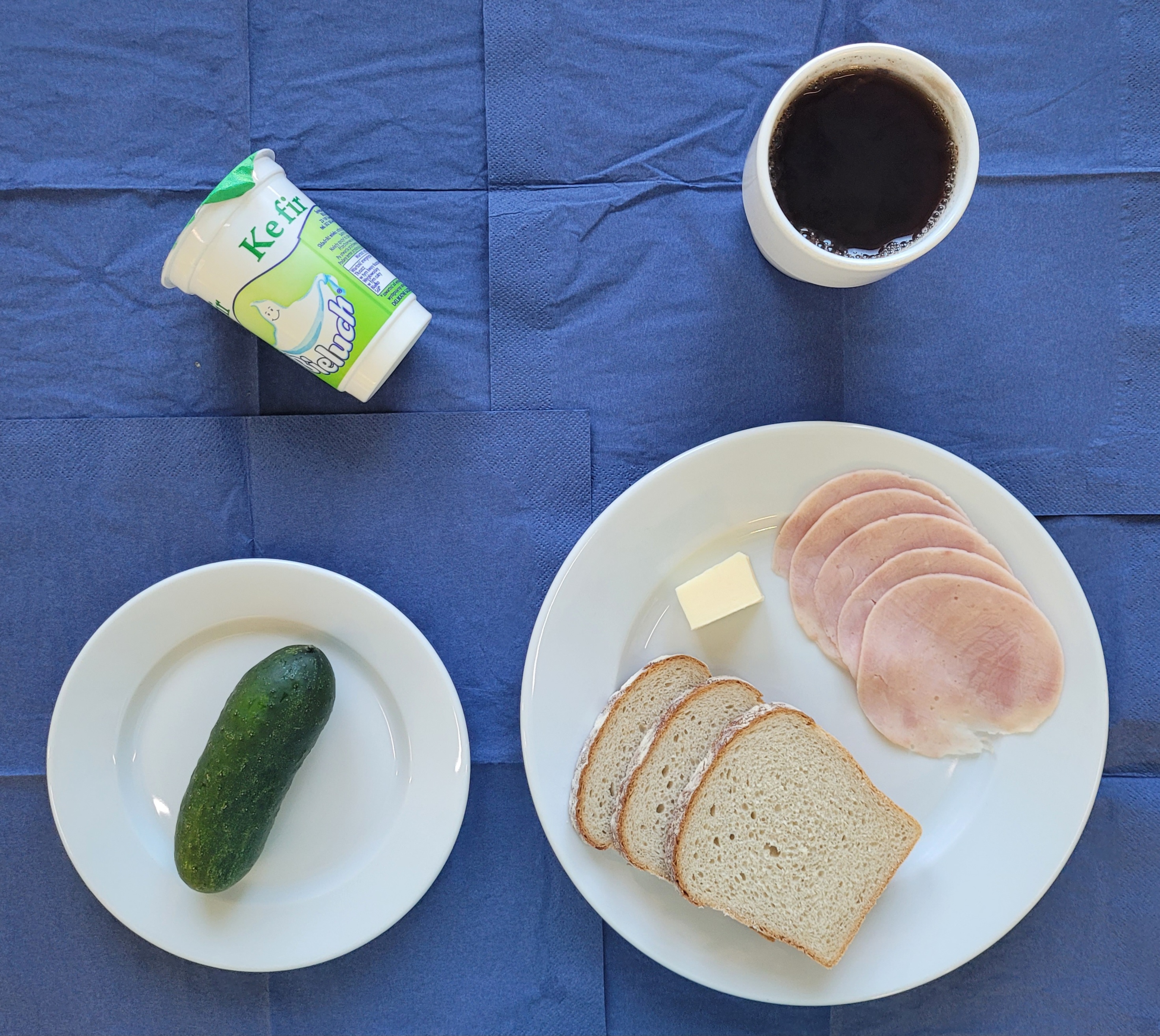 na talerzach szynkowa, chleb żytni, mało, ogórek, kefir, w kubku herbata z cytryną 
